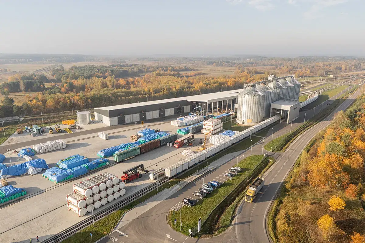 Magazyny i silosy zbożowe, kolejowe wagony towarowe i ciężarówki przygotowane do transportu drobnicowego.