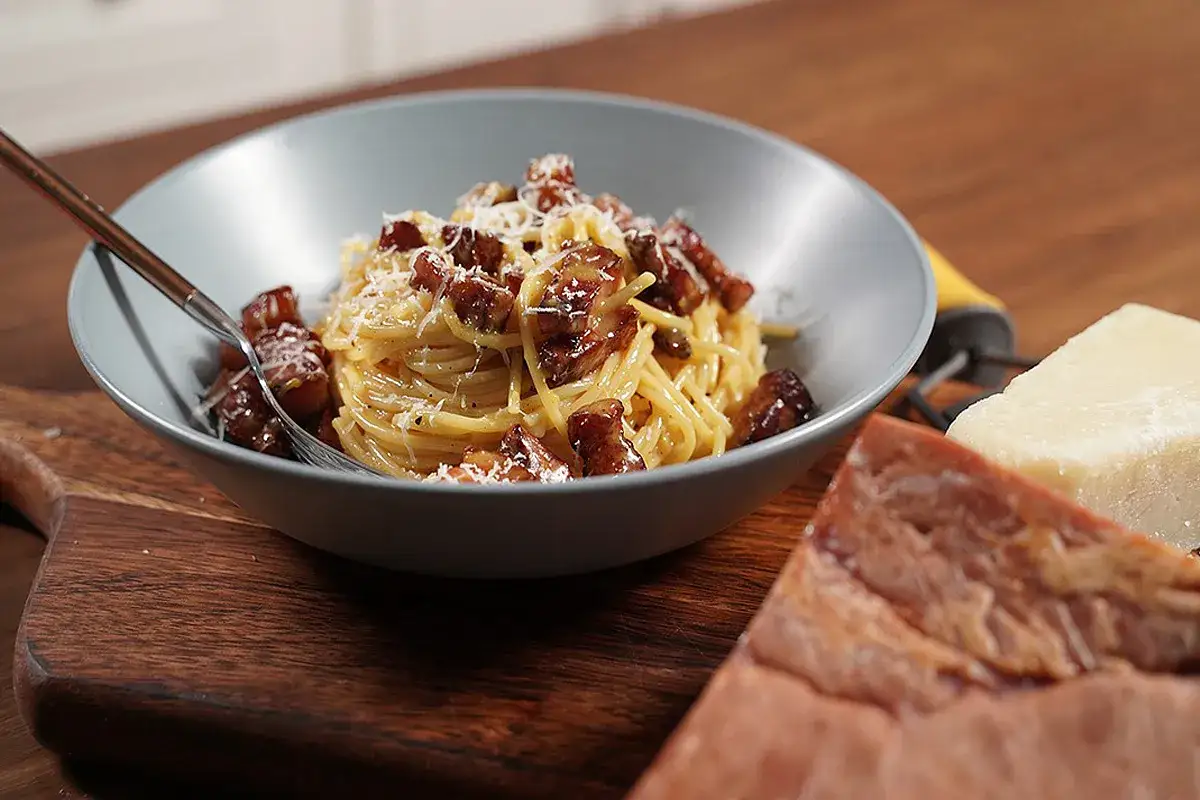 Un piatto di spaghetti con guanciale croccante, pecorino e pepe nero. Ingredienti freschi per un classico della cucina italiana.