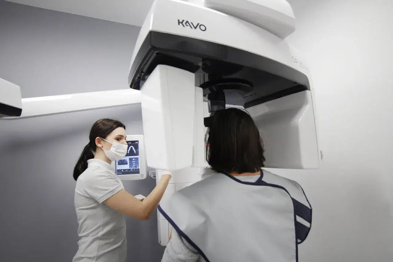 Dentystka przygotowuje pacjenta do badania CBCT, które pozwala uzyskać trójwymiarowy obraz szczęki.