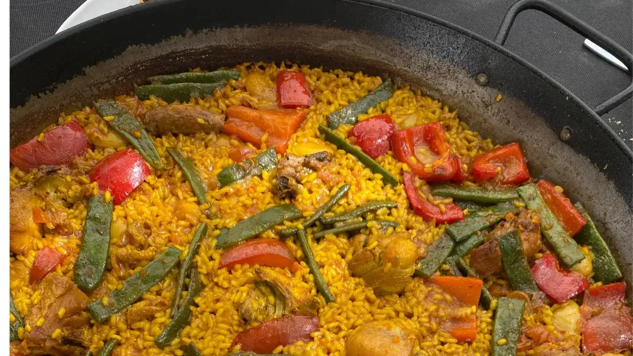 Pyszna paella, przepis oryginalny: ryż z kurczakiem, fasolką szparagową i papryką w złocistym kolorze.
