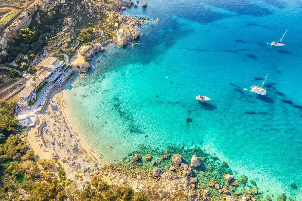 Malta plaże: złoty piasek, turkusowa woda i łodzie kołyszące się na falach. Idealne miejsce na wakacje.