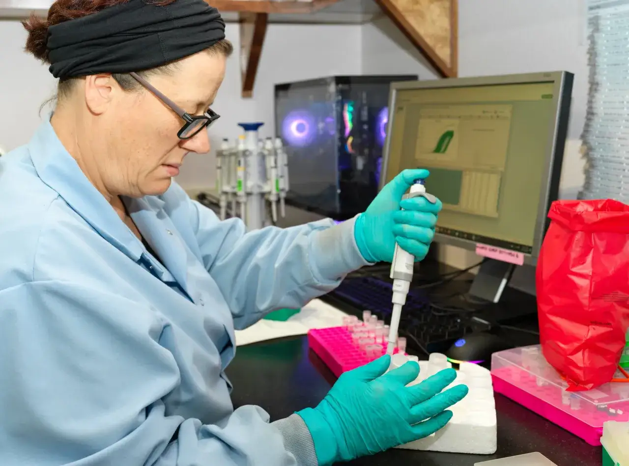 Naukowczyni w laboratorium analizuje próbki, by uzyskać wyniki. Na ekranie komputera widoczne są wykresy.