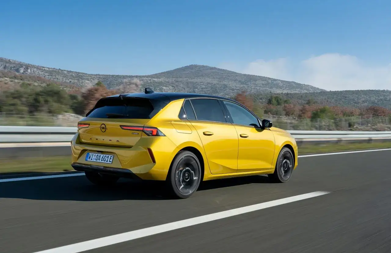 Opel Astra 1.6 CDTI 136 CV en amarillo vibrante, circulando por una carretera con monta&ntilde;as al fondo. Opiniones positivas para este modelo.