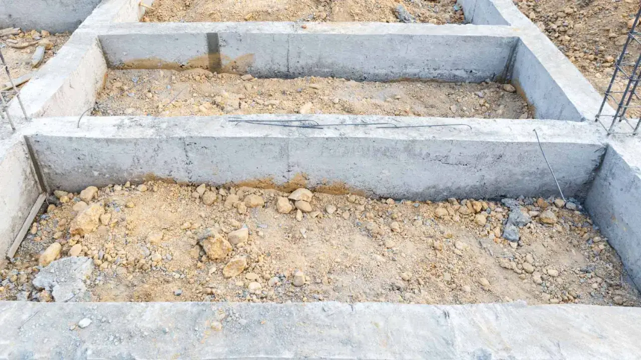 Fundament pod domek narzędziowy z bloczków betonowych. Widać zbrojenie i przygotowany teren.