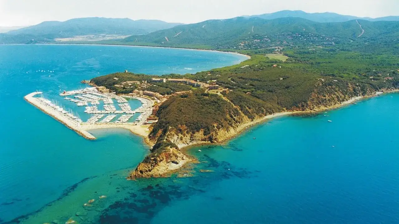 La punta ala cosa vedere: un porto turistico con yacht, una baia con acque cristalline e colline verdi.