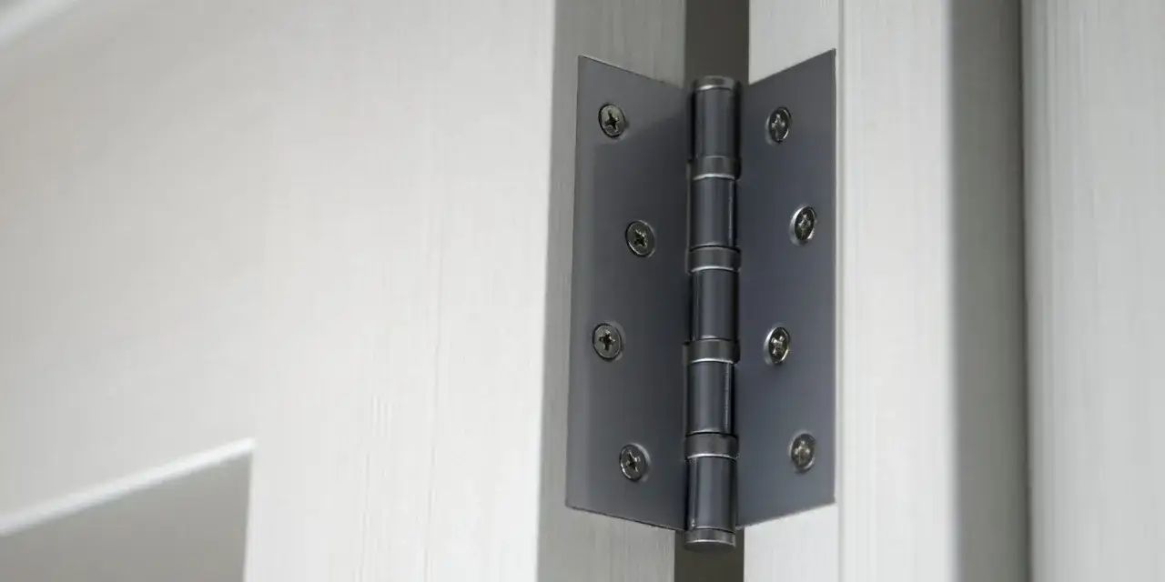 Charni&egrave;re de porte en m&eacute;tal fix&eacute;e &agrave; une porte blanche. On entendrait presque le grincement de cette porte qui s'ouvre.