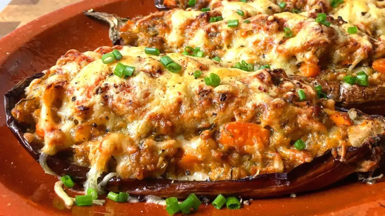 Berenjenas rellenas doradas y gratinadas, cubiertas con queso derretido y cebollino fresco. ¡Un plato delicioso y reconfortante!