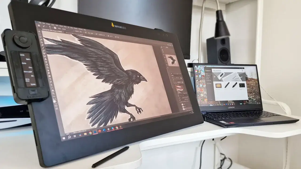 Artysta tworzy cyfrowego kruka na tablecie graficznym, korzystając z zaawansowanych aplikacji do rysowania. Obok stoi laptop z otwartym oprogramowaniem.