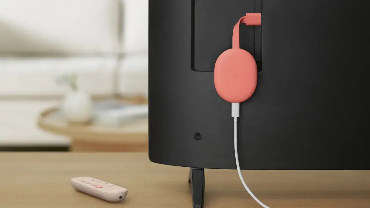 Różowy Chromecast podłączony do telewizora. Pilot leży obok. Dowiedz się, jak połączyć Chromecast z telefonem.
