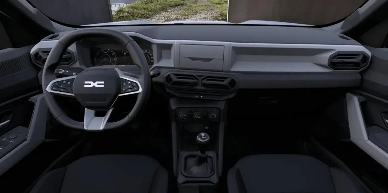 Wnętrze Dacia Duster 3: kierownica z logo, deska rozdzielcza z nawiewami i dźwignia zmiany biegów.
