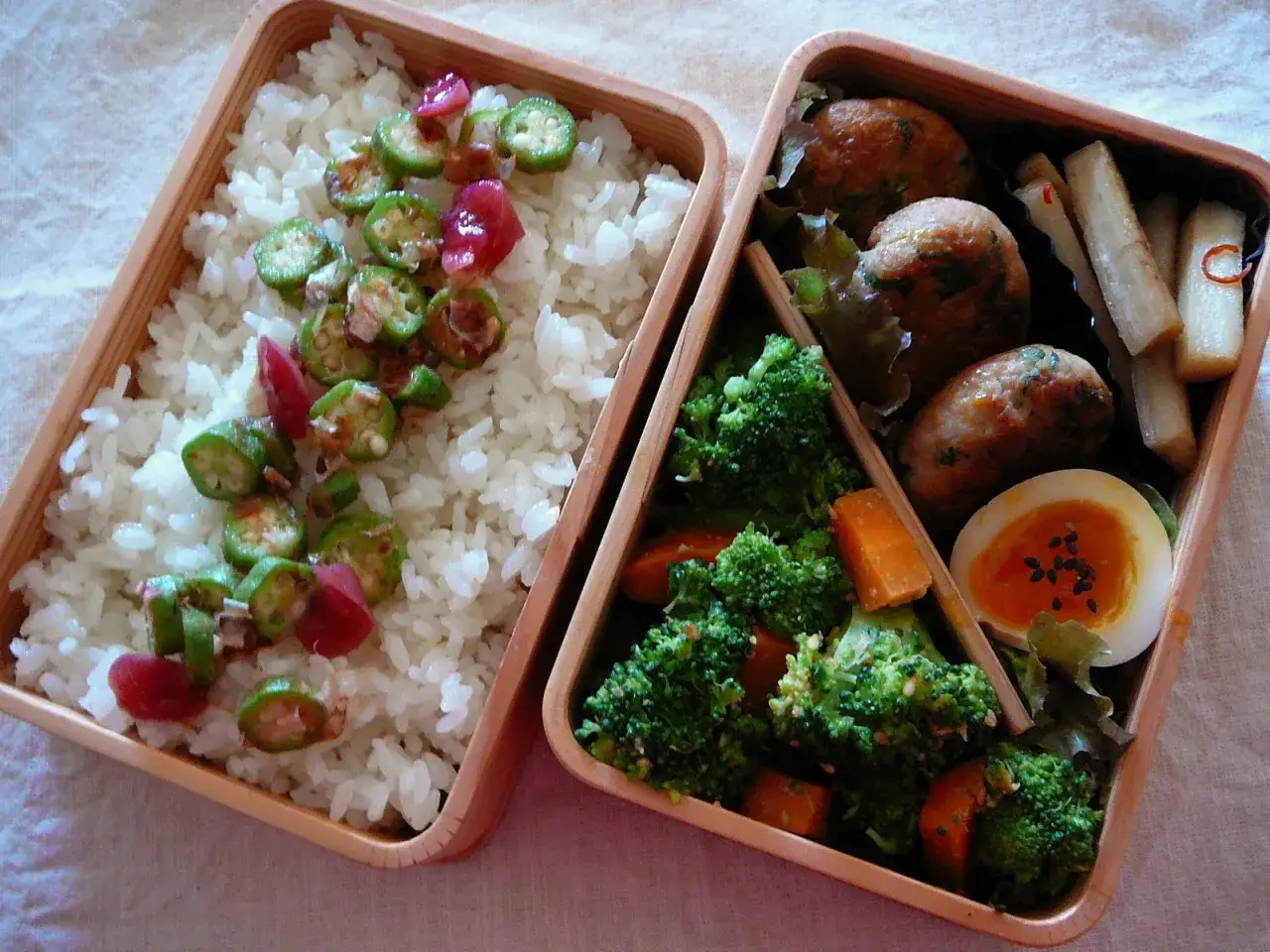 A delicious tuna bento box with rice, okra, broccoli, carrots, meatballs, and a soft-boiled egg.
