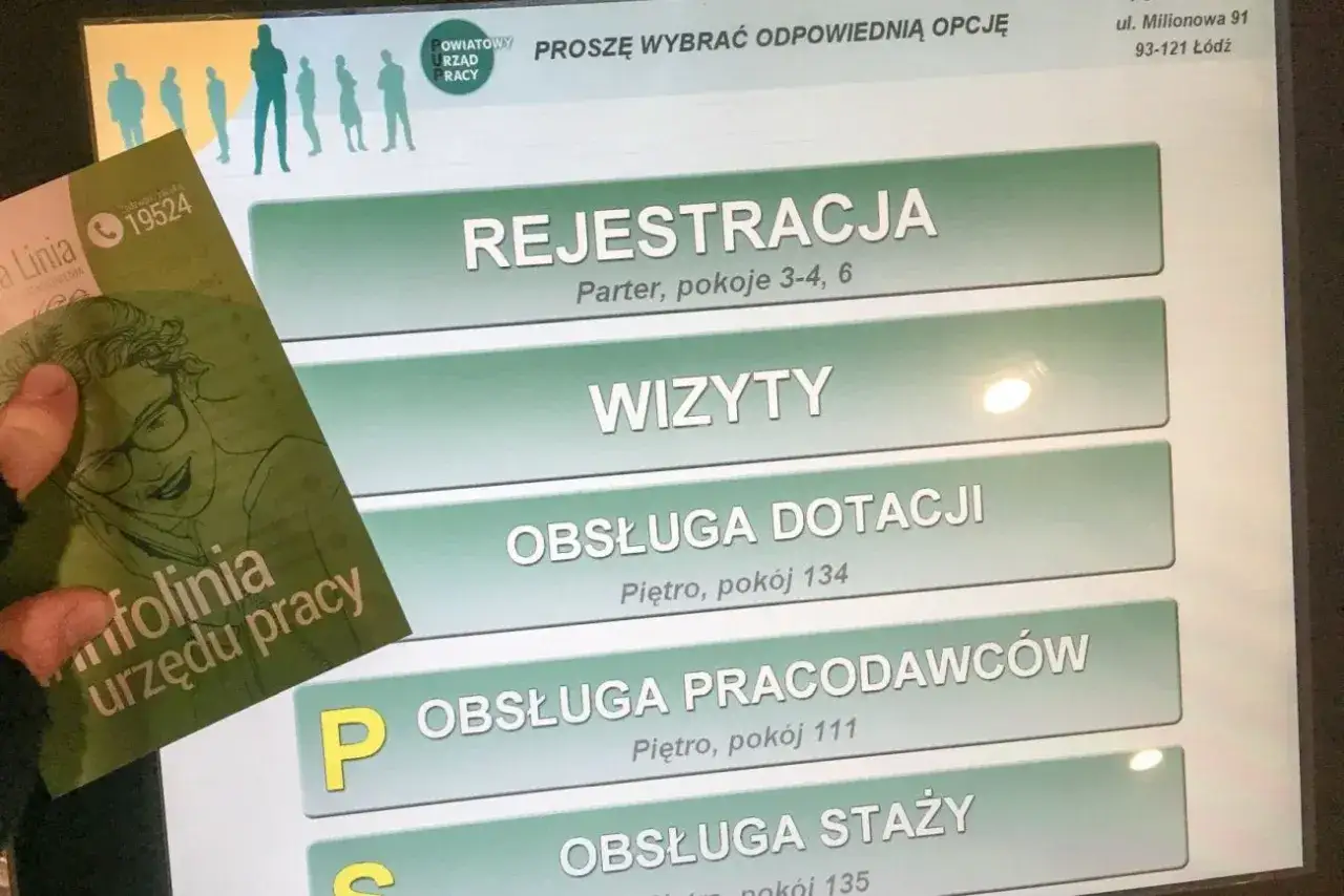 Dłoń trzyma ulotkę z infolinią urzędu pracy. Na ekranie terminala widnieje menu: 