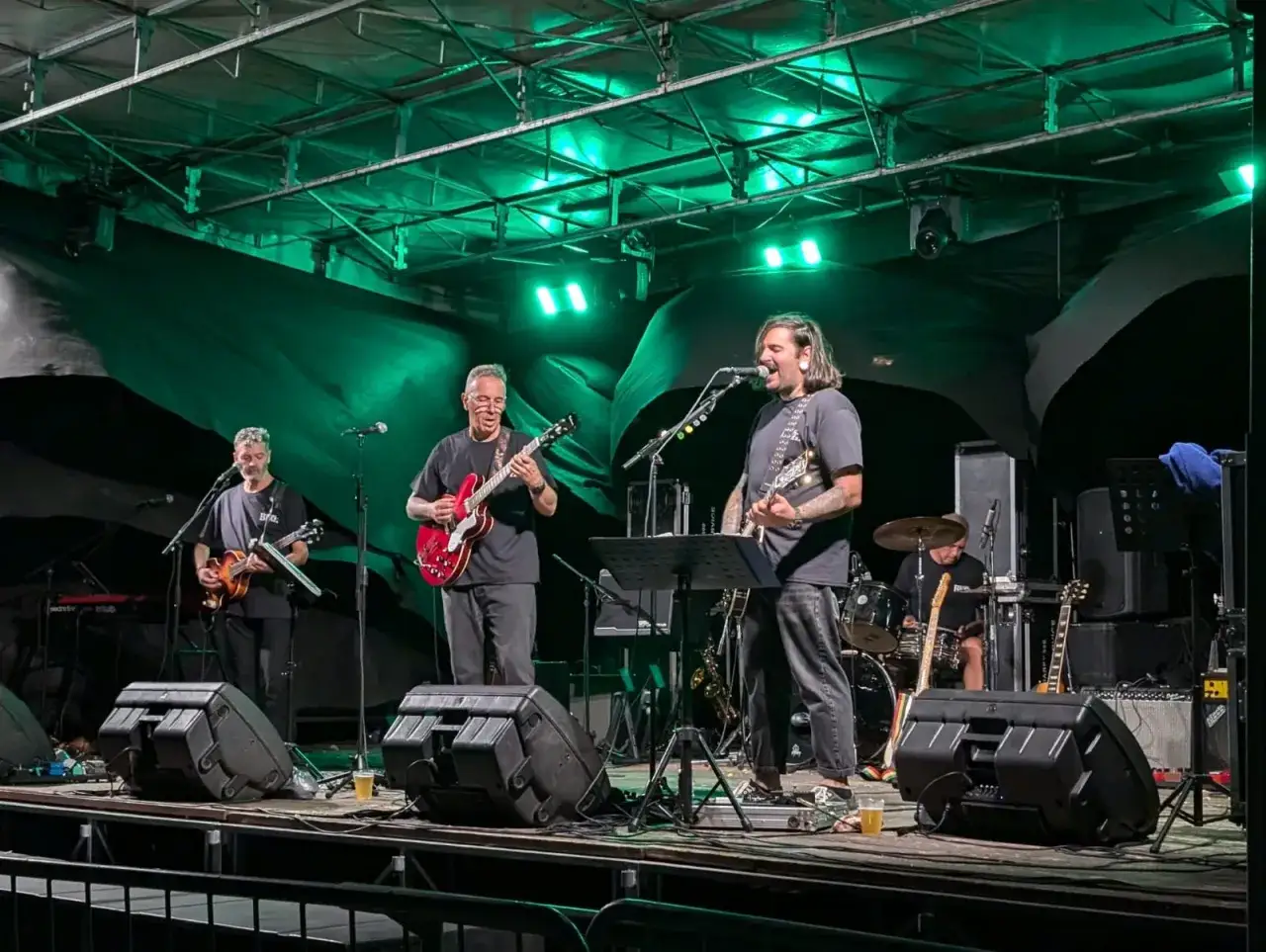 Quattro musicisti su un palco illuminato di verde, con chitarre e batteria. Un assaggio dei gruppi musicali veneti famosi.