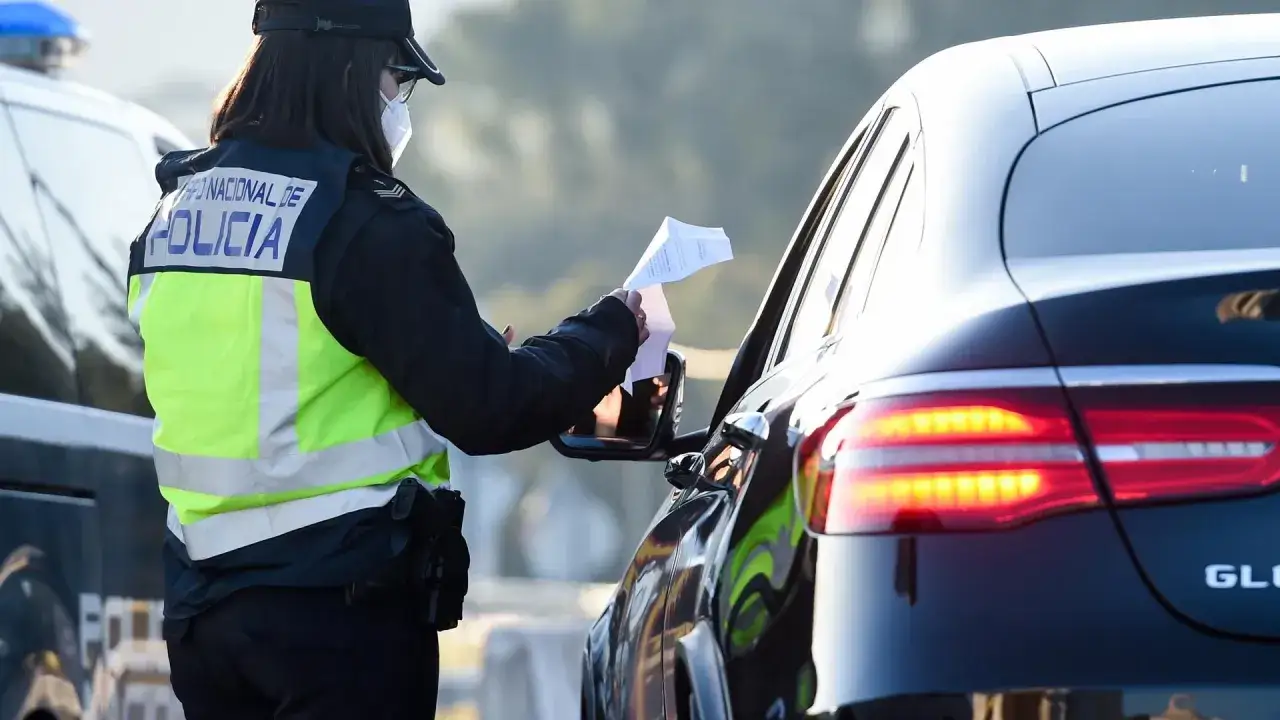 Agente de polic&iacute;a revisa documentos, sospechando de un carnet de conducir falso.