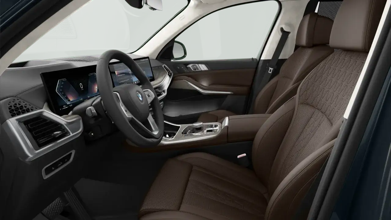 Wnętrze luksusowego BMW X7 z brązową skórzaną tapicerką, nowoczesnym panelem cyfrowym i kierownicą.
