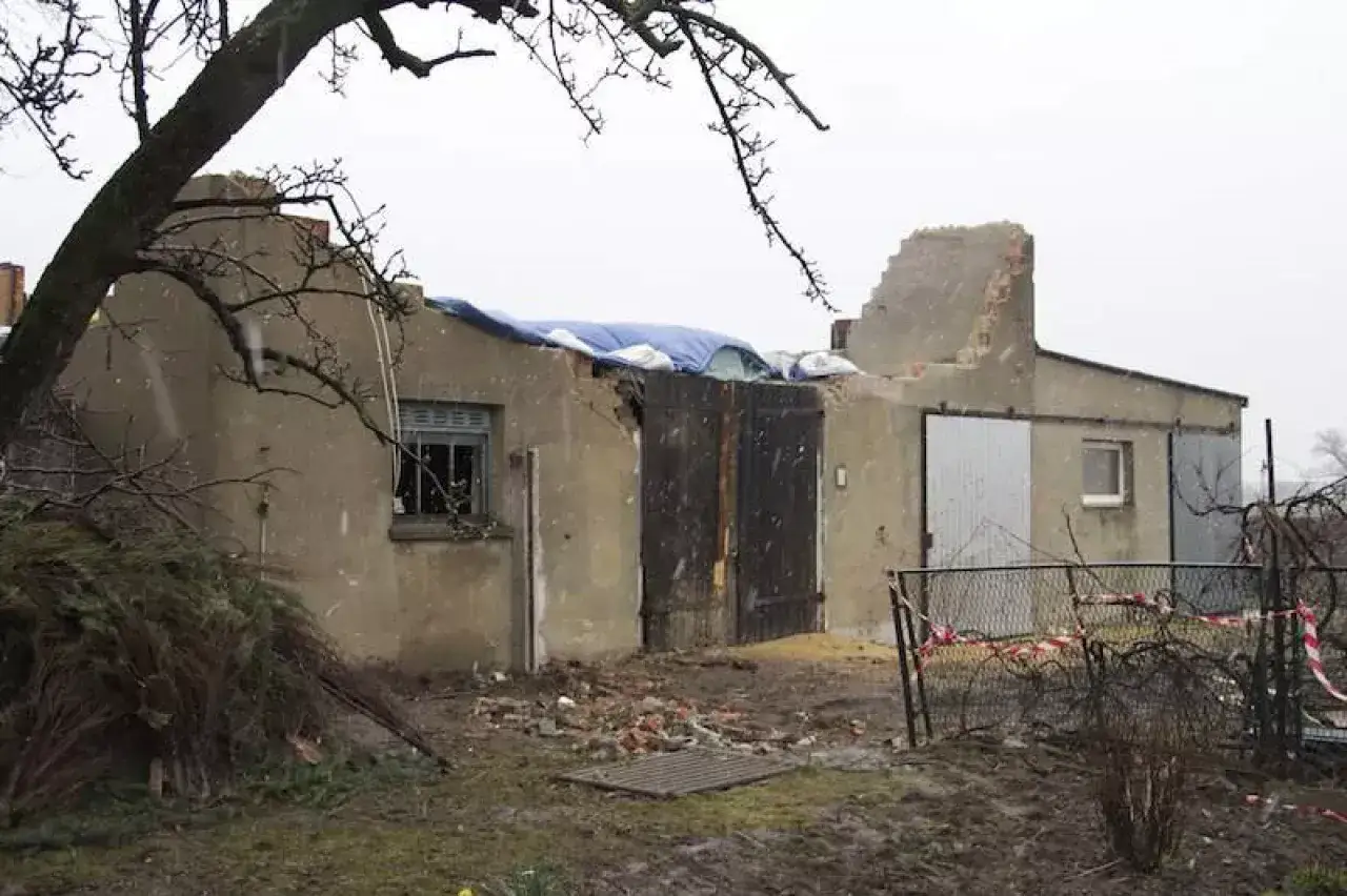 Drzewo sąsiada przewróciło się na moją działkę, niszcząc dach budynku gospodarczego. Widać gruzy, plandekę na dachu i uszkodzone drzwi.
