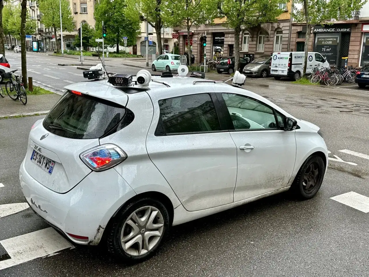 Voiture blanche &eacute;quip&eacute;e d'un radar embarqu&eacute; et de cam&eacute;ras sur le toit, pr&ecirc;te &agrave; surveiller la circulation.
