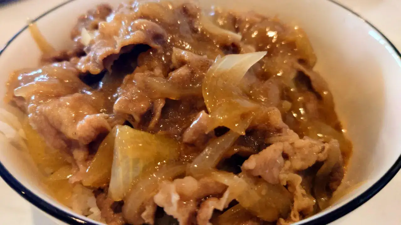 A close-up of a delicious Yoshinoya beef bowl recipe, featuring tender beef and sweet onions simmered in a savory sauce over rice.