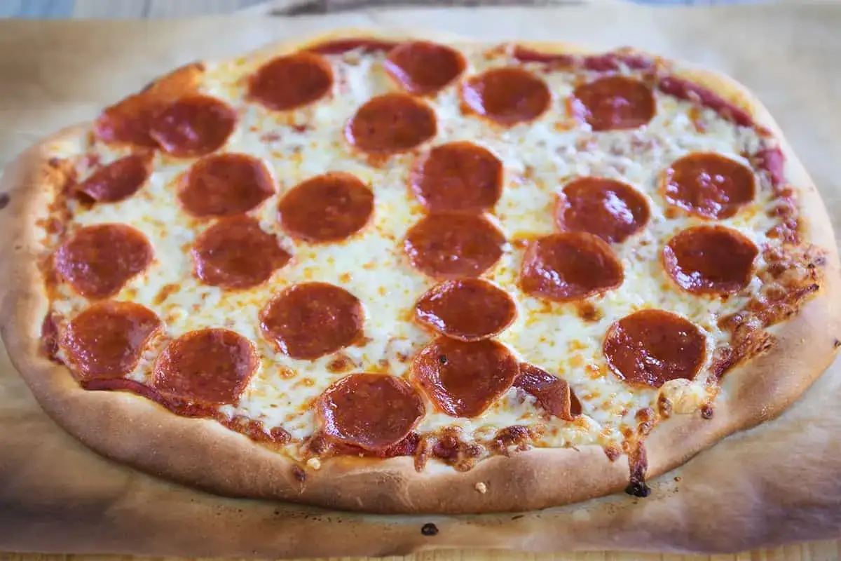 Pyszne ciasto na pizzę bez wyrastania, z serem i pepperoni, gotowe do podania.
