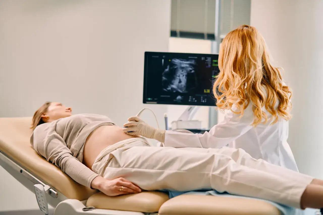 Lekarka wykonuje badanie USG ciężarnej pacjentki, patrząc na monitor.