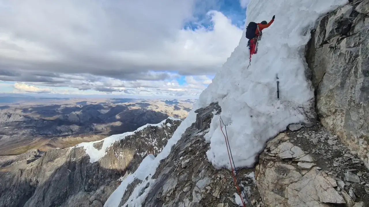 Escalador en hielo desafía la montaña, con un **bru busom** de nieve y roca bajo un cielo nublado.