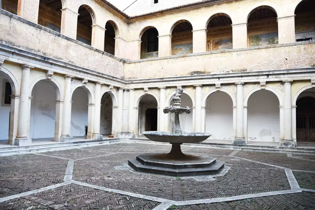 Cortile della Certosa di Padula con fontana centrale e portici ad archi.