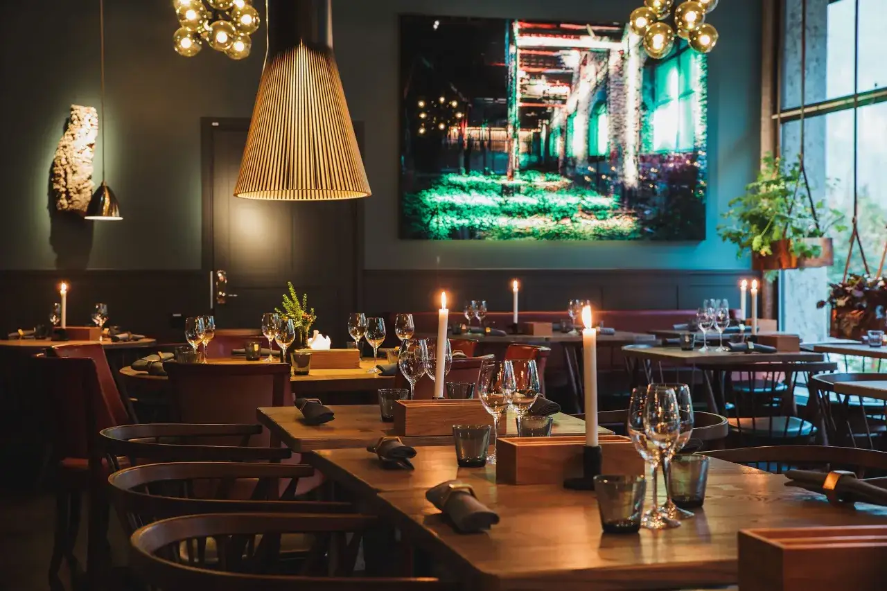 Vackert dukade bord med levande ljus och vinglas p&aring; en fin restaurang i Stockholm. En stor tavla med industriellt motiv pryder v&auml;ggen.