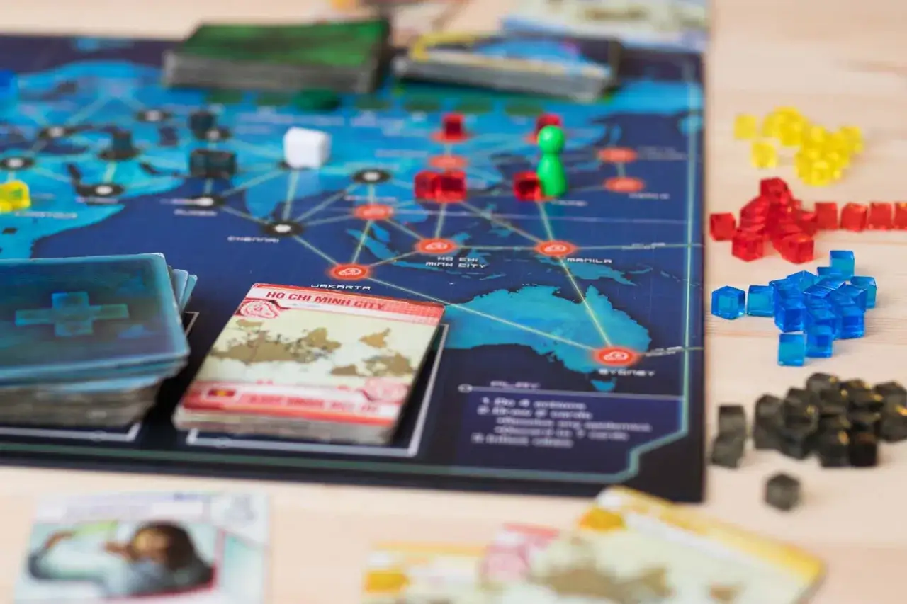 Plansza do gry Pandemic, z kostkami symbolizującymi choroby i kartami miast. Idealne fajne gry dla dorosłych, by poczuć się jak bohater ratujący świat.