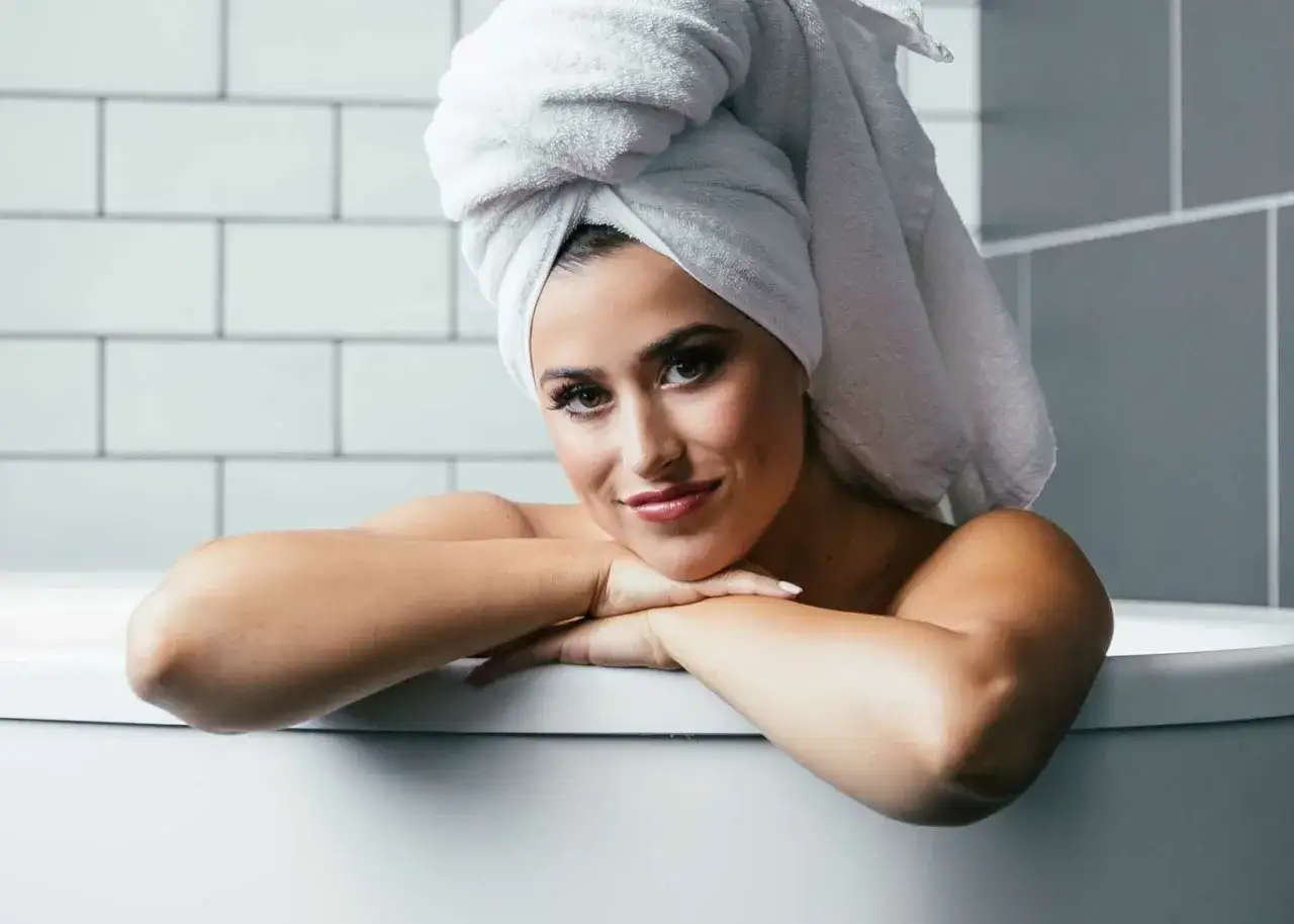Frau mit Handtuch auf dem Kopf entspannt in der Badewanne. Die Wirkung eines Natronbades kann Wunder wirken f&uuml;r Haut und Wohlbefinden.