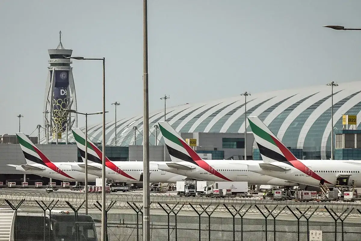 Samoloty dubajskich linii lotniczych Emirates stojące na płycie lotniska przed nowoczesnym terminalem.
