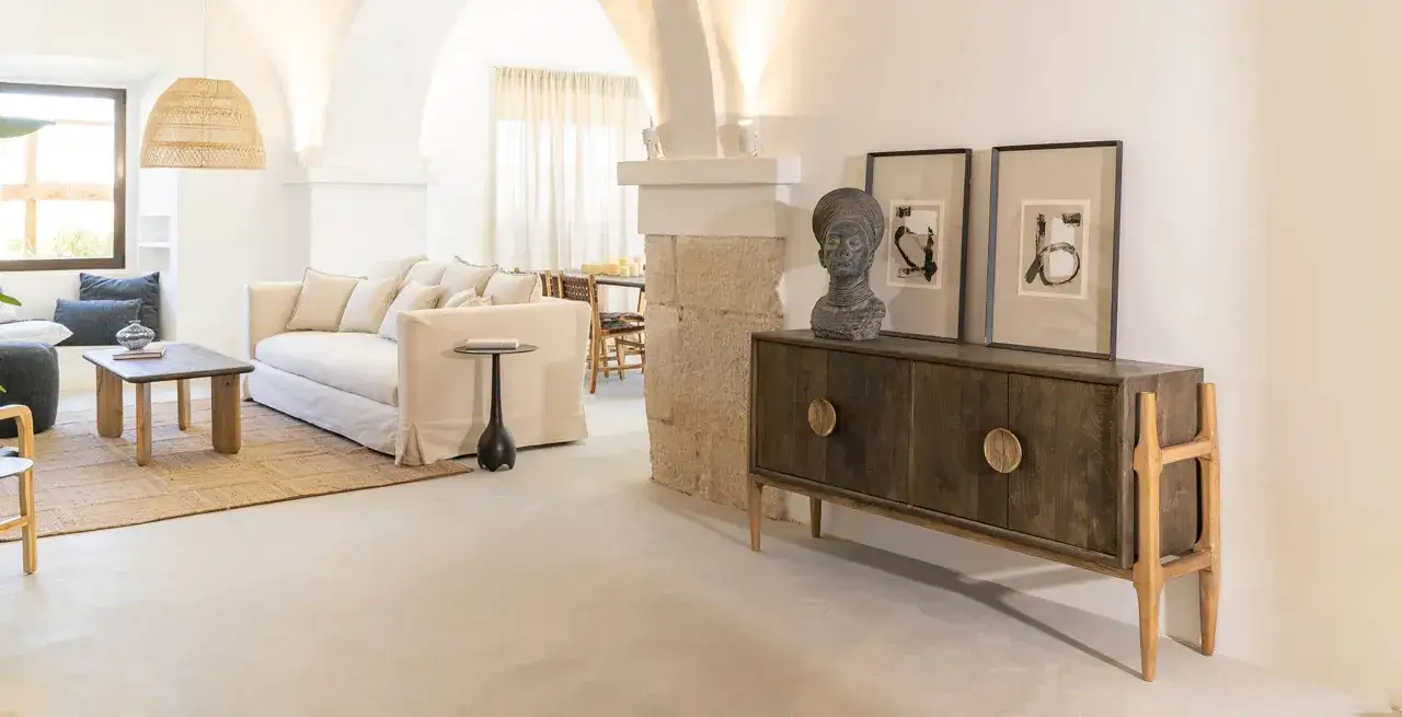 Muebles de estilo asi&aacute;tico con un sof&aacute; blanco, mesa de centro de madera y un aparador oscuro con detalles dorados.