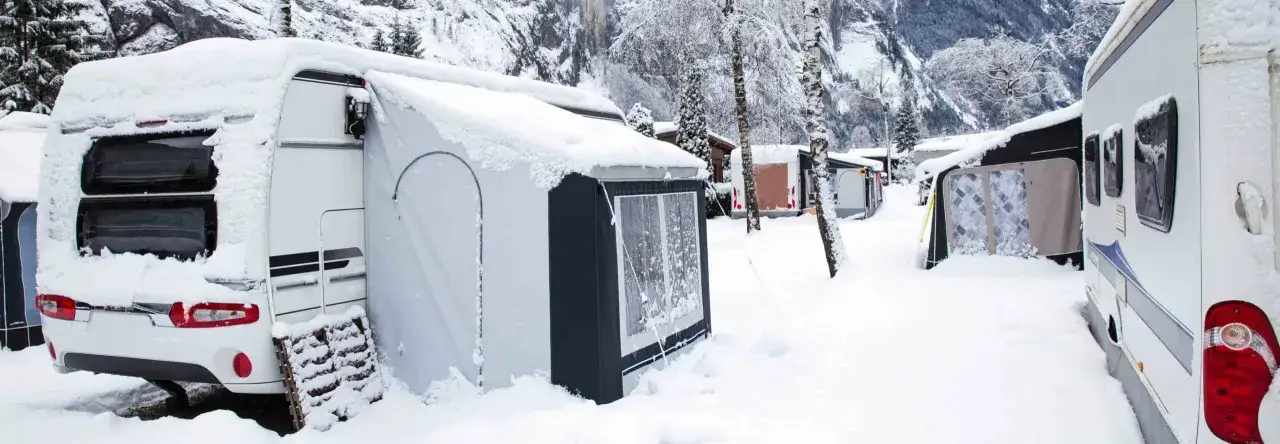 Schneebedeckte Wohnwagen und Vorzelte auf einem Campingplatz im Erzgebirge. Wintercamping pur!