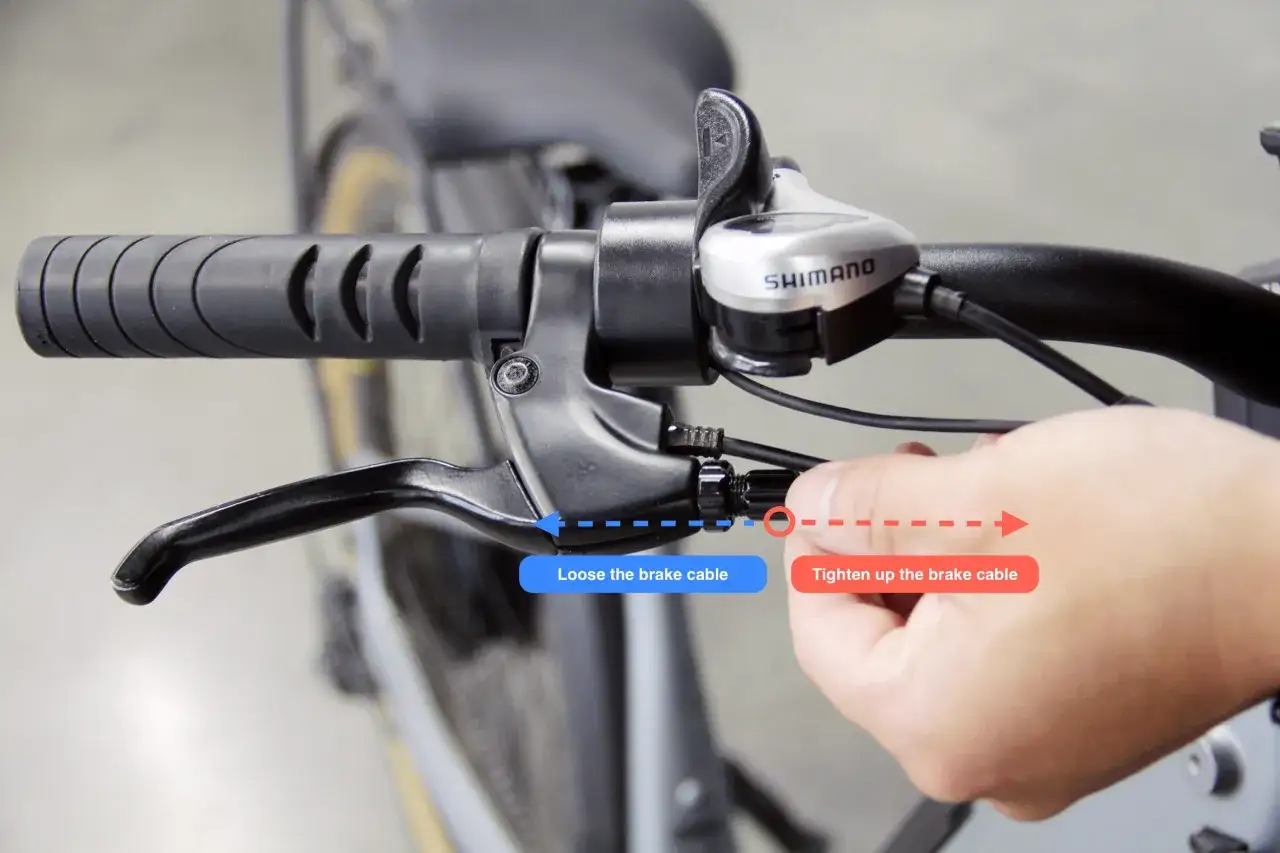 Jak wyregulować hamulce w rowerze: dłoń dokręca linkę hamulca przy manetce Shimano.