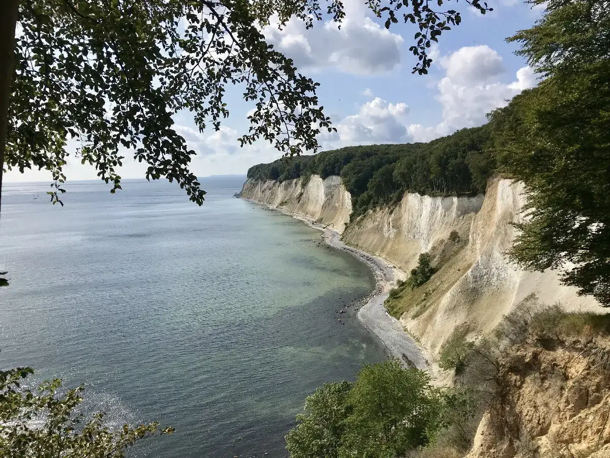 Weiße Kreidefelsen und grüne Wälder an der Küste von Rügen, Deutschland, blicken auf das ruhige Meer.