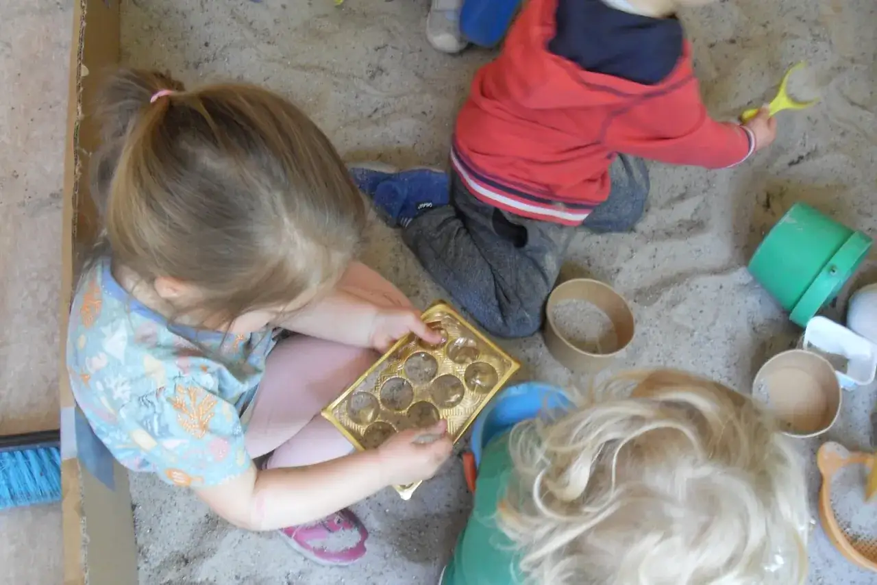 Kinder genie&szlig;en spielzeugfreie Zeit in der Kita und bauen im Sandkasten.