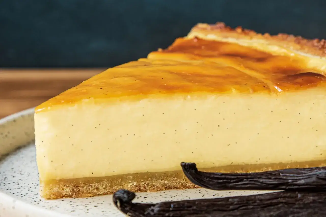 Une part de flan p&acirc;tissier grand-m&egrave;re, cr&eacute;meux et vanill&eacute;, sur une assiette avec des gousses de vanille.