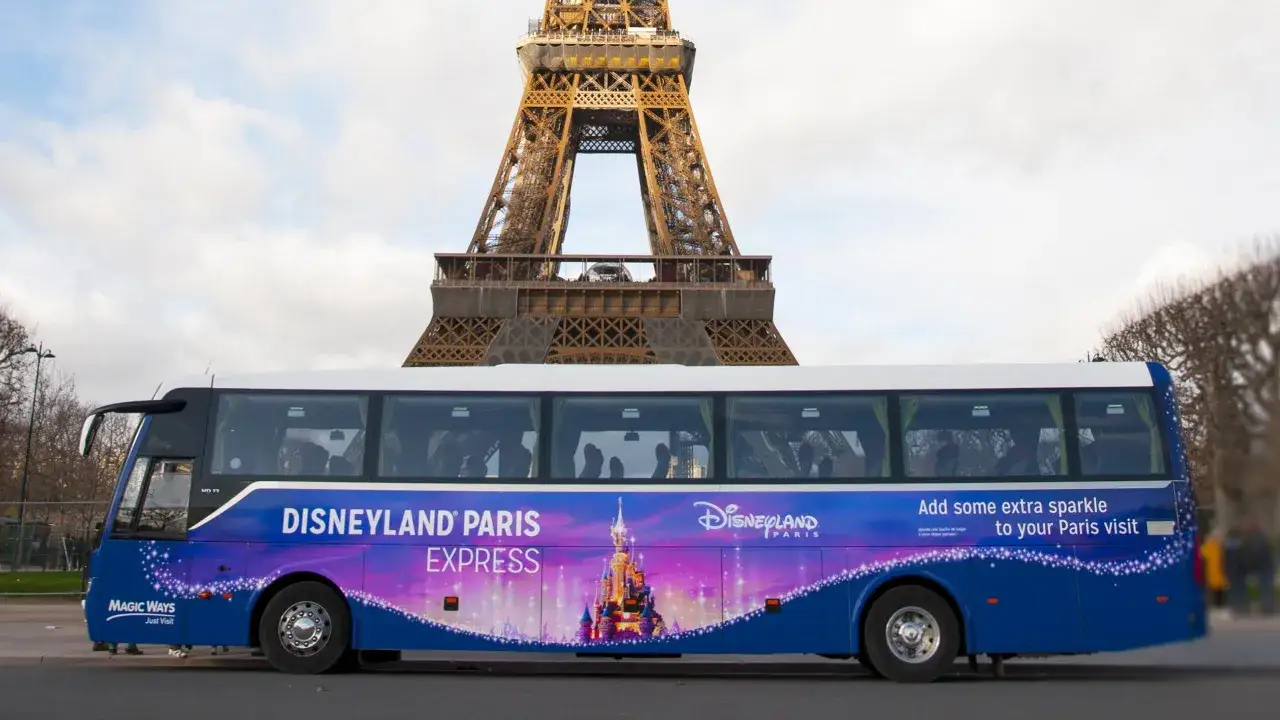 Un bus Disneyland Paris Express, avec le château féerique, passe devant la Tour Eiffel.