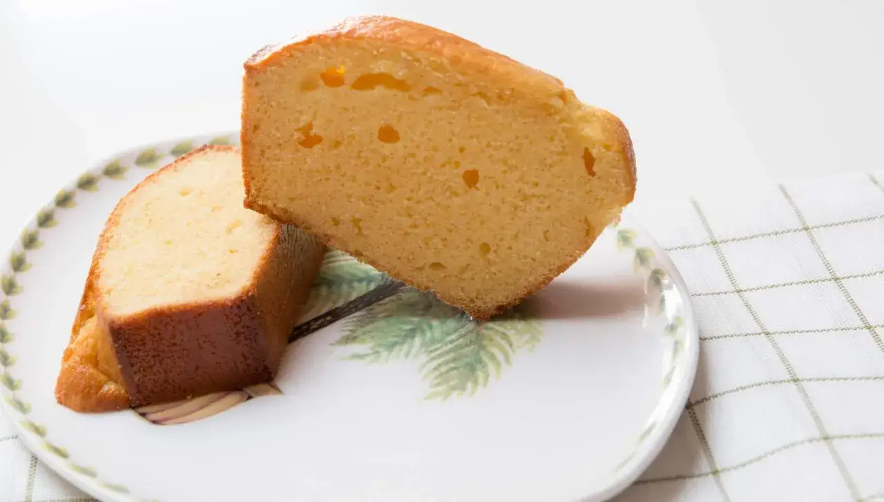 Dos rebanadas de bizcocho de leche condensada, esponjosas y doradas, servidas en un plato con diseño de palmeras.