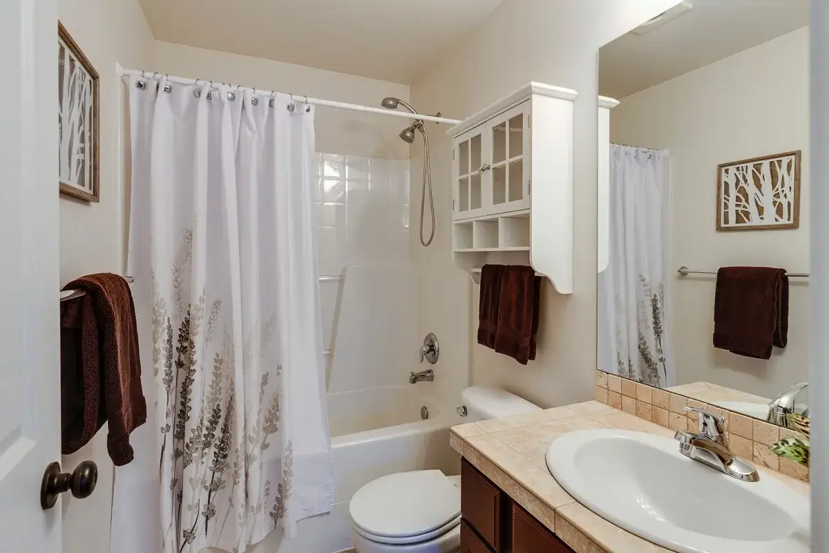 Bagno cieco con doccia, vasca, WC e lavandino. La tenda della doccia ha un motivo floreale. L'aerazione bagno cieco è garantita da un sistema a scomparsa.