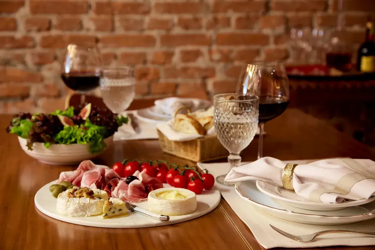 Plateau de fromages, charcuterie, tomates cerises et salade. Un verre de vin rouge suggère quel vin avec le fromage pour un repas parfait.