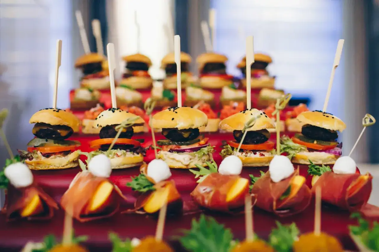 Mini burgery i zawijane przekąski z szynką parmeńską na eleganckim szwedzkim stole.