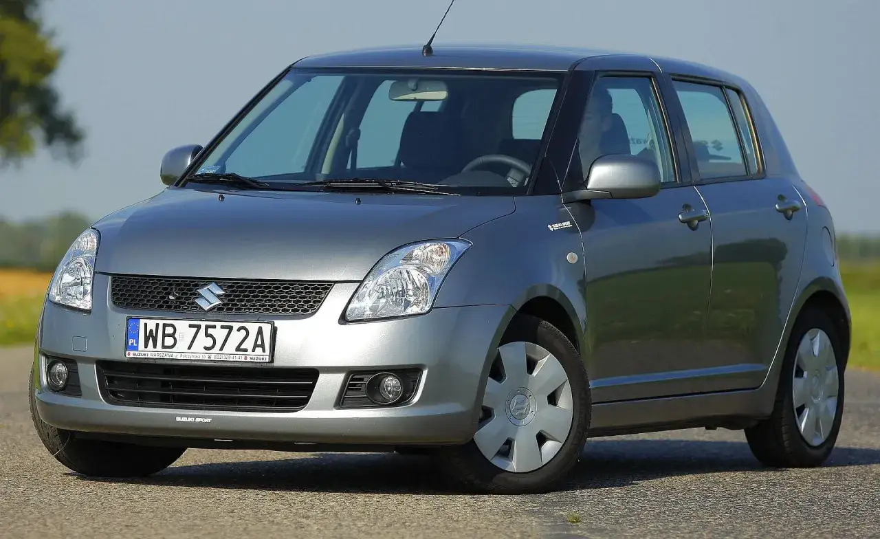 Szary Suzuki Swift, idealny na pierwsze samochody do 10 tys. zł. Zgrabny, miejski hatchback z polskimi tablicami rejestracyjnymi.