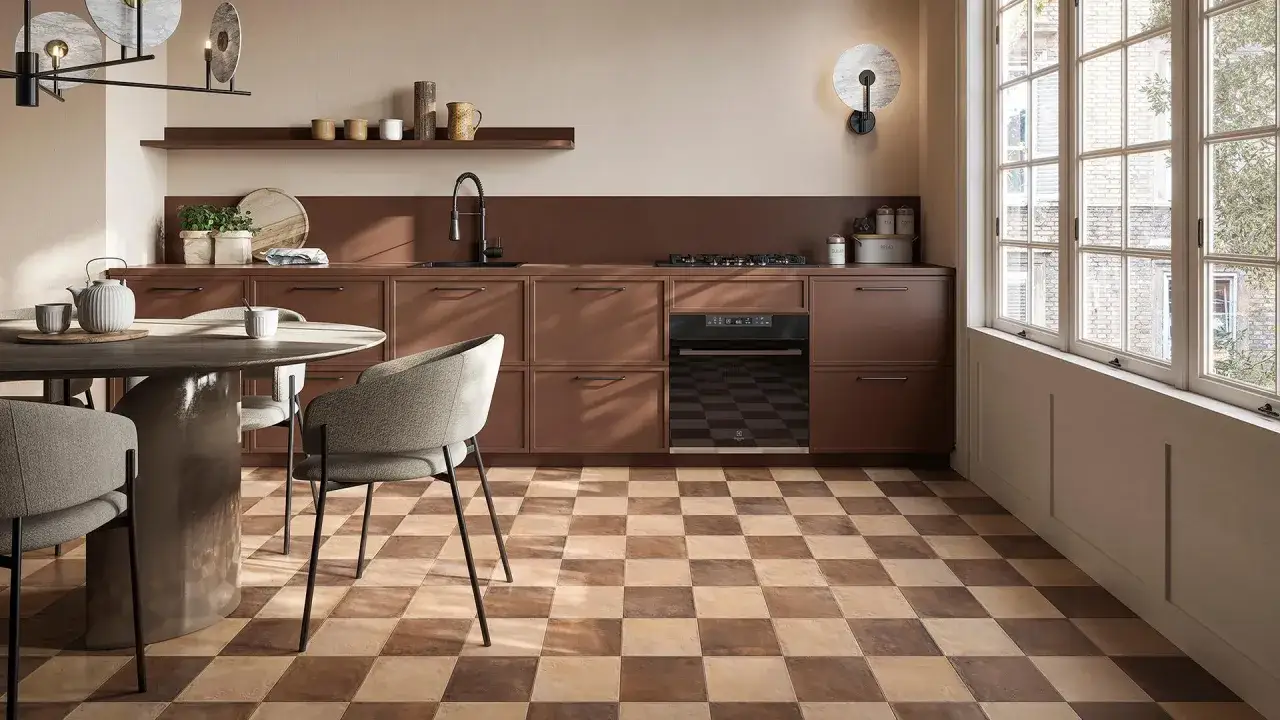Cucina moderna con pavimento a scacchiera che crea una **tabella colori caldi**. Mobili marroni, tavolo rotondo e sedie grigie.