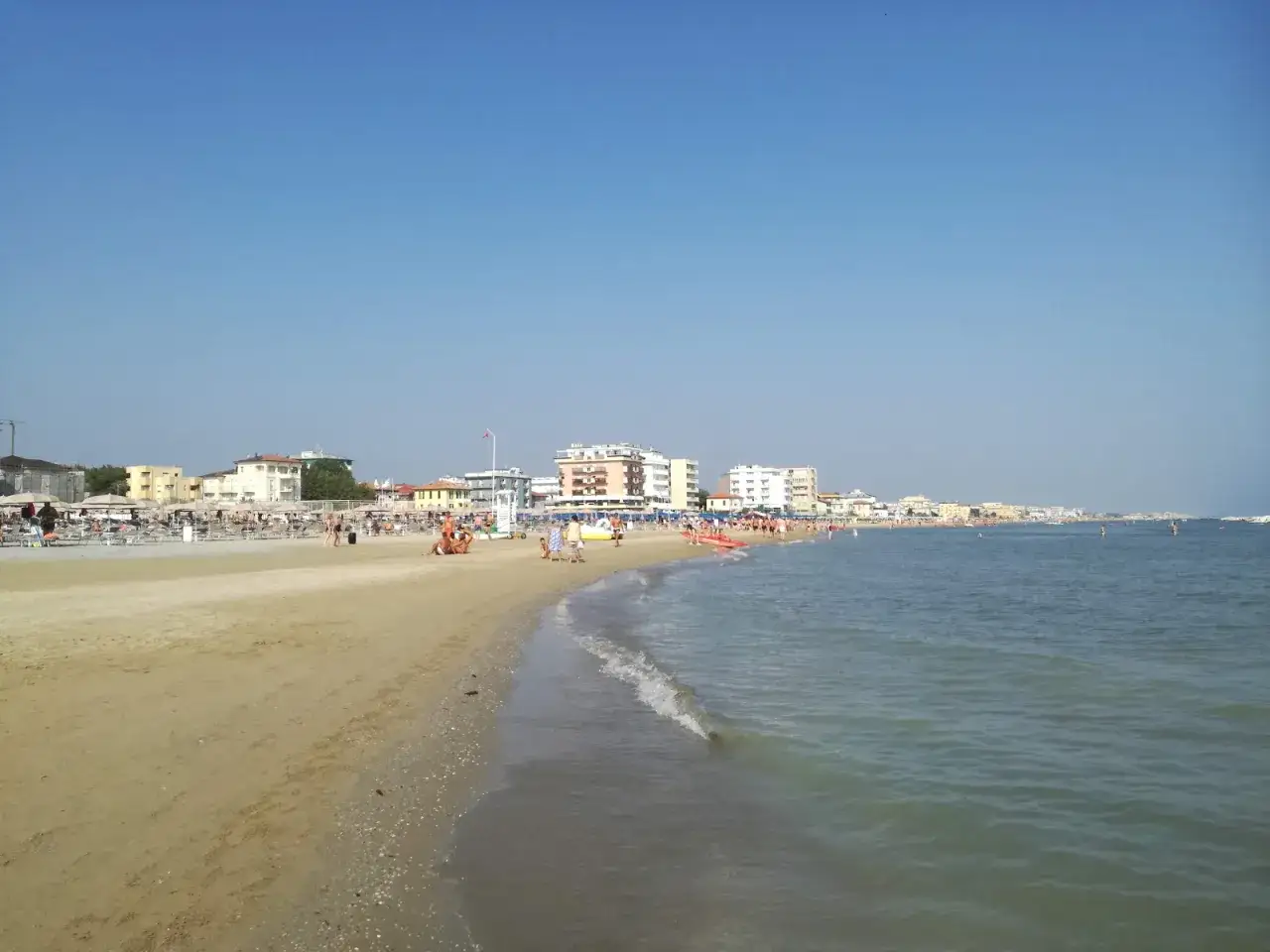 Spiaggia affollata a Viserbella, con ombrelloni, lettini e persone che si godono il mare Adriatico sotto un cielo azzurro.