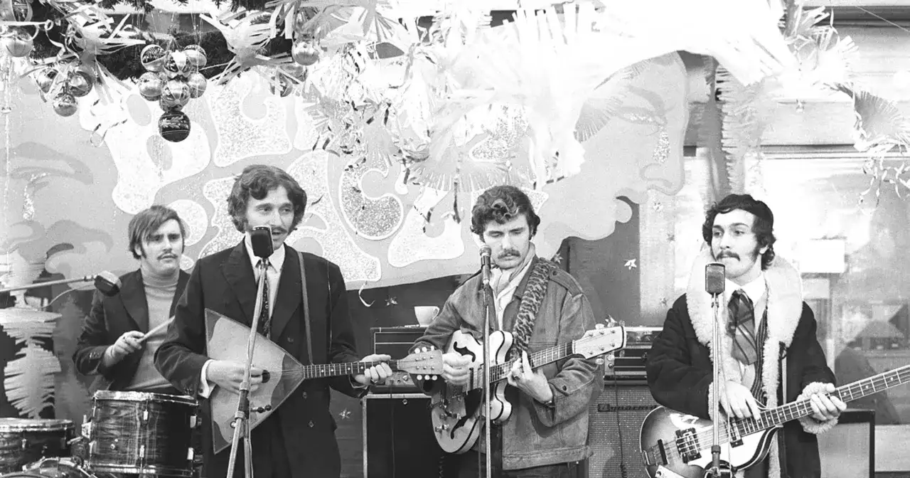 Krzysztof Krawczyk z zespołem na scenie, grający na gitarach i balalajce.