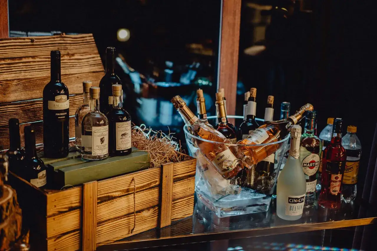 Elegancki alkohol na 50 urodziny: wino, prosecco i mocniejsze trunki w lodzie i drewnianej skrzyni.
