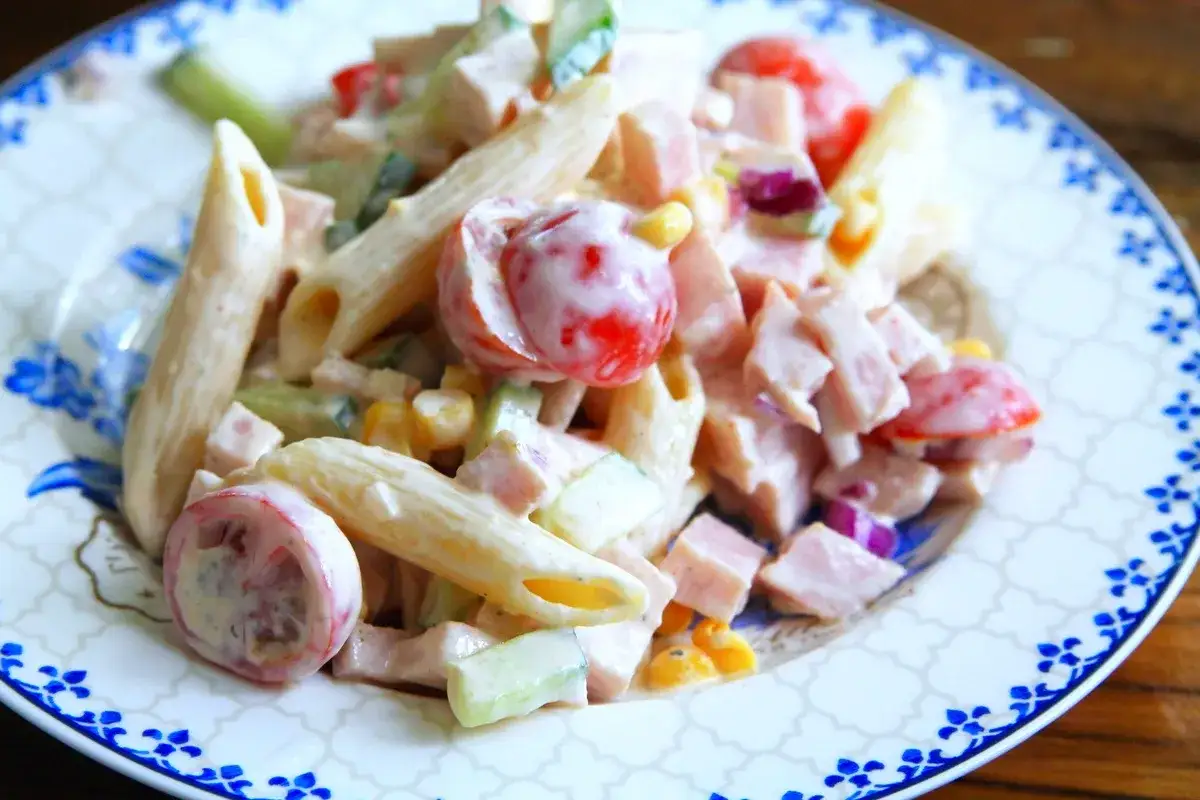 En krämig pastasallad med skinka, penne, körsbärstomater, gurka och majs. Perfekt för en snabb lunch eller middag.