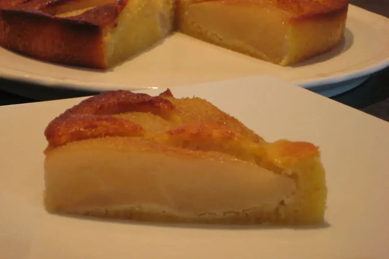 Tranche de gâteau poire amandine, avec des morceaux de poire fondants et une croûte dorée.
