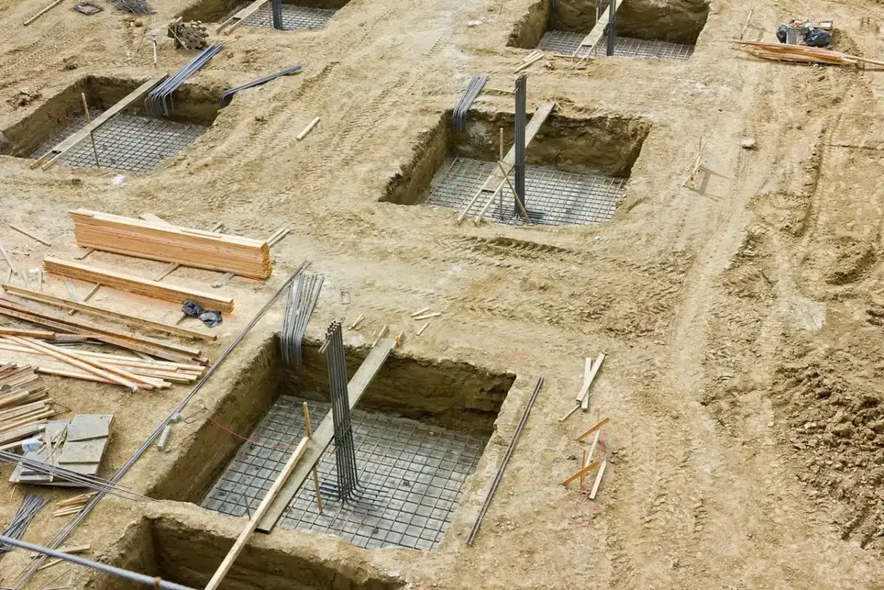 Rozpoczęto podbijanie fundamentów. Wykopane doły z zbrojeniem i drewnem budowlanym czekają na beton.