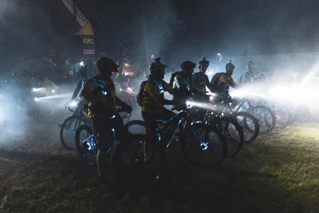Ciclisti illuminati nella notte, pronti a pedala coi lupi in un'avventura notturna.